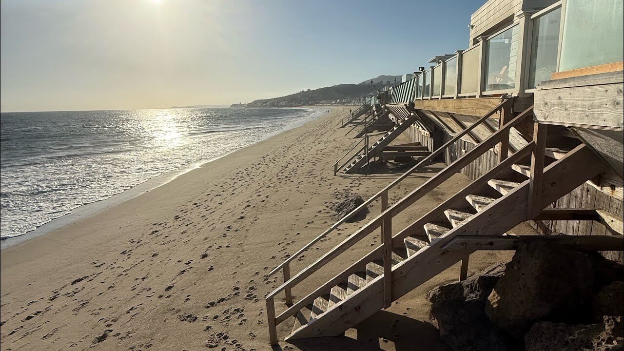Plage de Malibu au coucher du soleil avec des maisons en bois sur pilotis donnant directement sur le sable