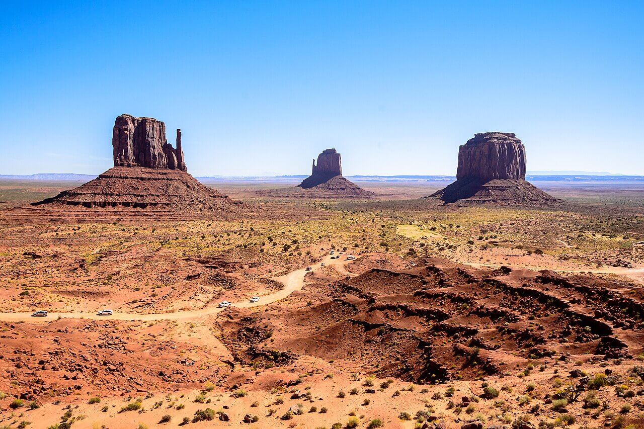 Les trois buttes emblématiques de Monument Valley sous ciel bleu dans le désert rouge Arizona-Utah