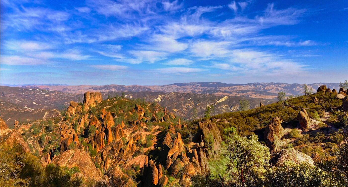 Formations volcaniques rouge-orang&eacute; du parc national des Pinnacles avec vue panoramique sur la vall&eacute;e et ciel dramatique