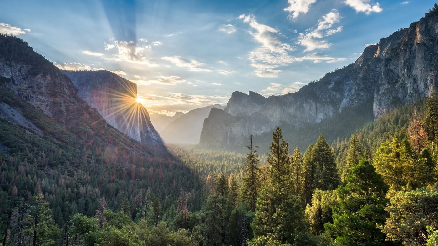 Lever de soleil sur la vall&eacute;e de Yosemite avec rayons lumineux derri&egrave;re El Capitan et for&ecirc;ts de pins